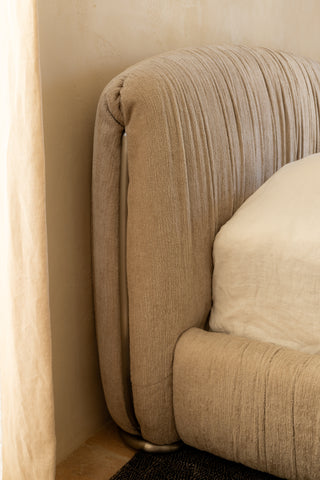 Beige textured Kew bedhead with a pillow against a beige wall