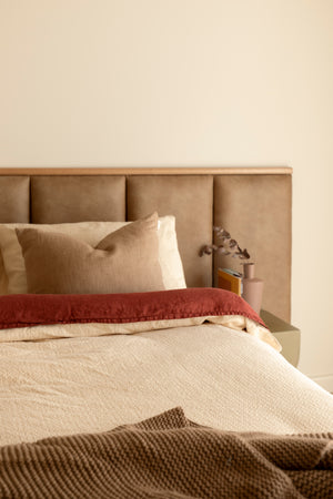 Brown leather bed head with feature timber top, in a warm cosy bedroom