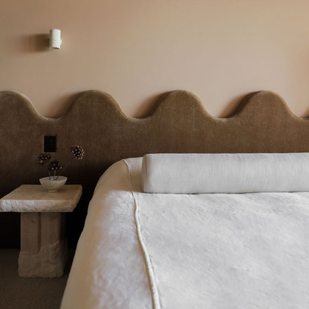 Brown leather bed head with feature timber top, in a warm cosy bedroom