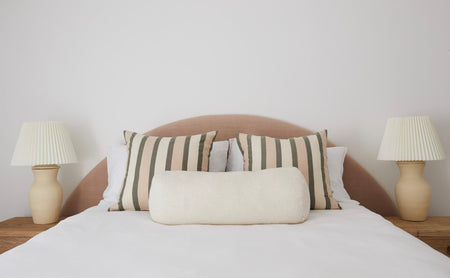 Pink Linen Bed Head in unique Half Moon shape with striped cushions in front and matching lamps on the side tables