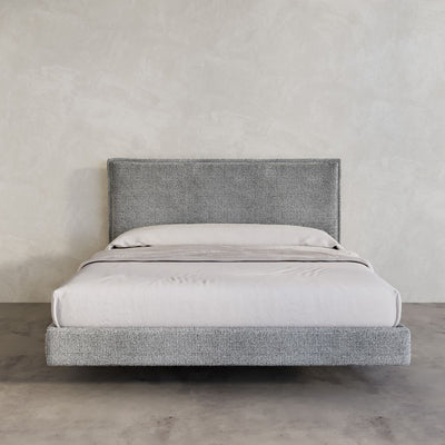 Stockholm Bed Frame in a chunky grey Wool Fabric pictured in a high end room with micro cement walls