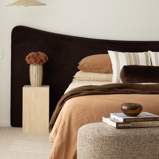 Modern chocolate floating bed frame with a side table, and decorative items.
