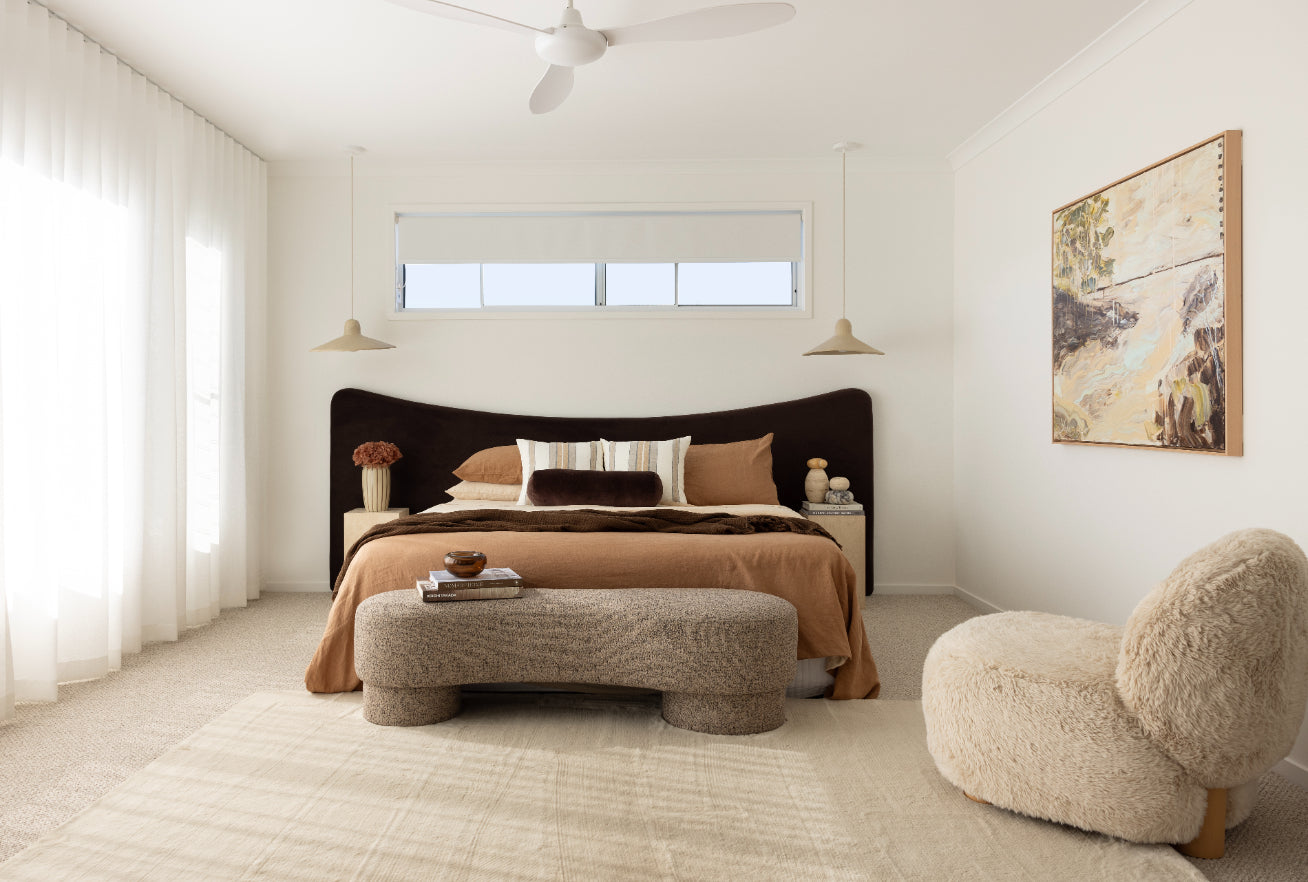 Modern master bedroom with a brown oversized bed, ottoman, and decorative items.