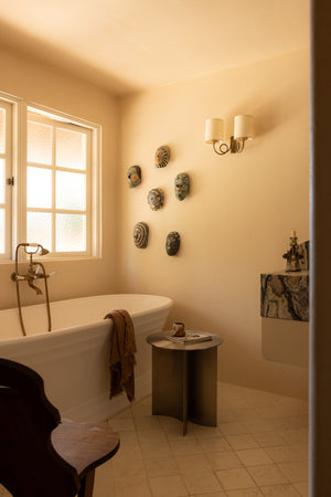 Bathroom with freestanding bathtub, wall decorations, and stainless steel side table.