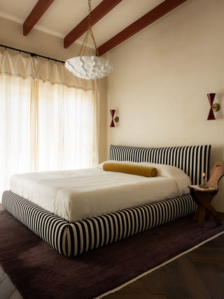 Bedroom with a bed featuring a black and white striped bed and white bedding.