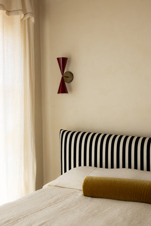 Bedroom with striped headboard and red wall sconce