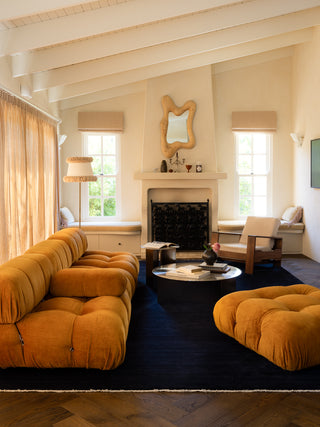 Living room with mustard yellow sofa, ottoman, and fireplace.
