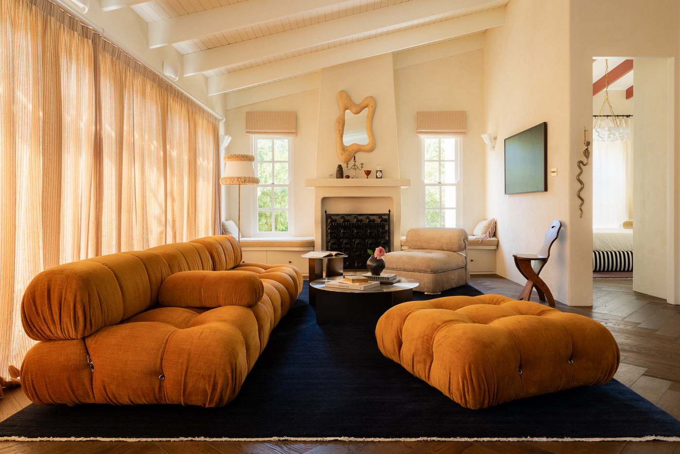 Modern french inspired living room with vintage sofa and ottoman on a dark rug.