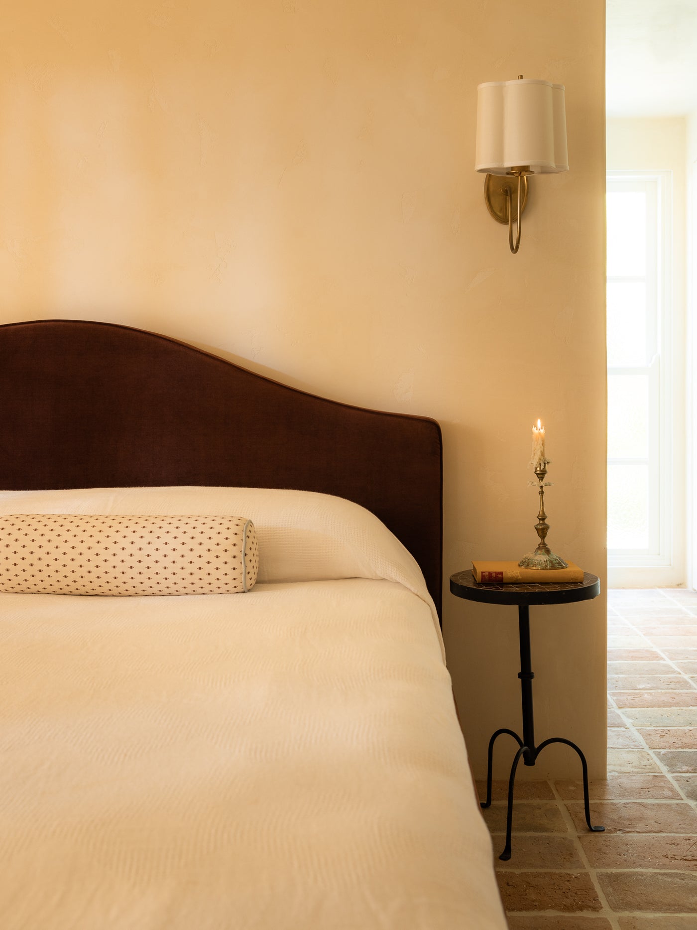 Bedroom with a burgundy bed, nightstand, and wall lamp.
