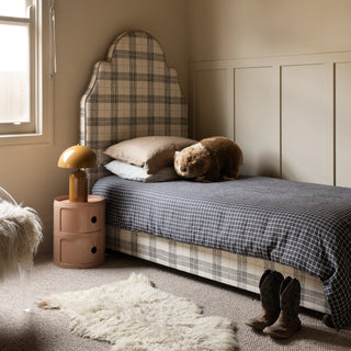 Bedroom with plaid headboard, checkered bedspread, and teddy bear.