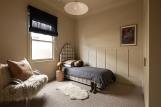 Children's bedroom with a bed, chair, and window.