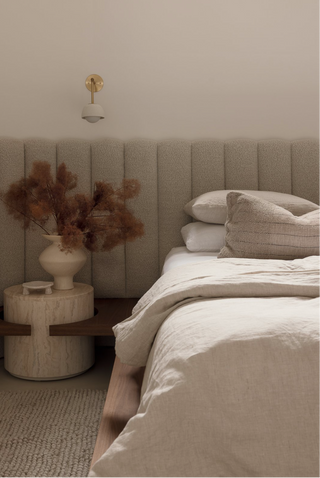 timber and boucle platform bed with built in travertine bedside table