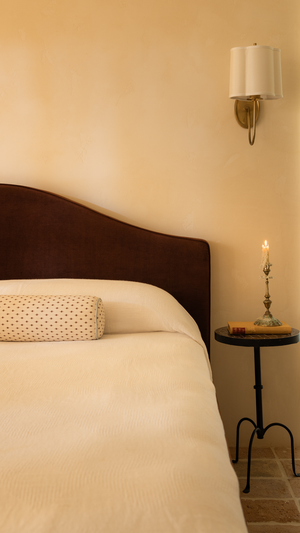 Bedroom with a bed, burgundy headboard, and side table with a candle.
