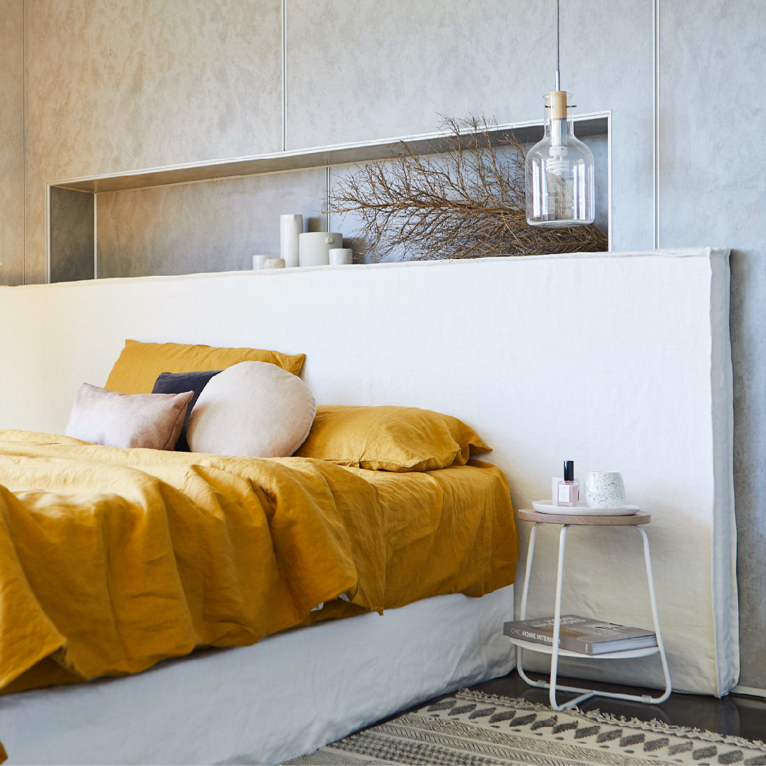 Wide bed head in white linen, pictured in a master bedroom against concrete walls