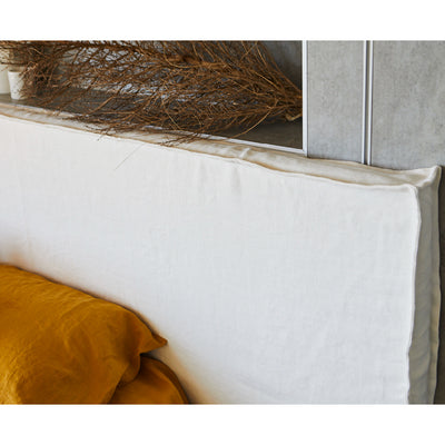 Wide bed head in white linen, pictured in a master bedroom against concrete walls