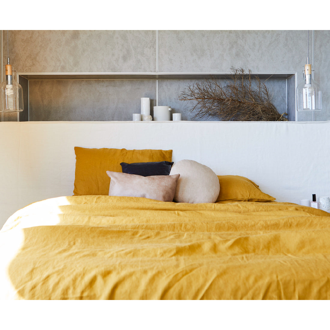 Wide bed head in white linen, pictured in a master bedroom against concrete walls