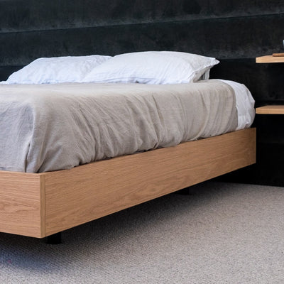 Floating bed base in American Oak, with a green velvet bed head in a master bedroom