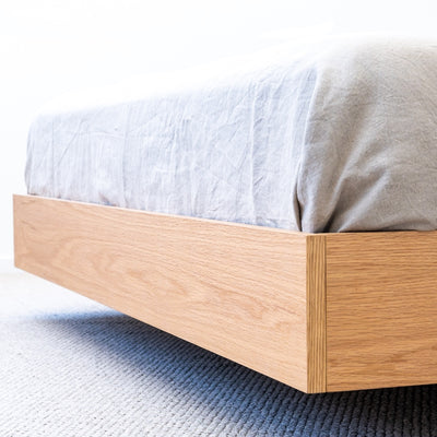 Floating bed base in American Oak, with a green velvet bed head in a master bedroom