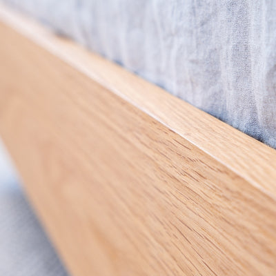 Floating bed base in American Oak, with a green velvet bed head in a master bedroom