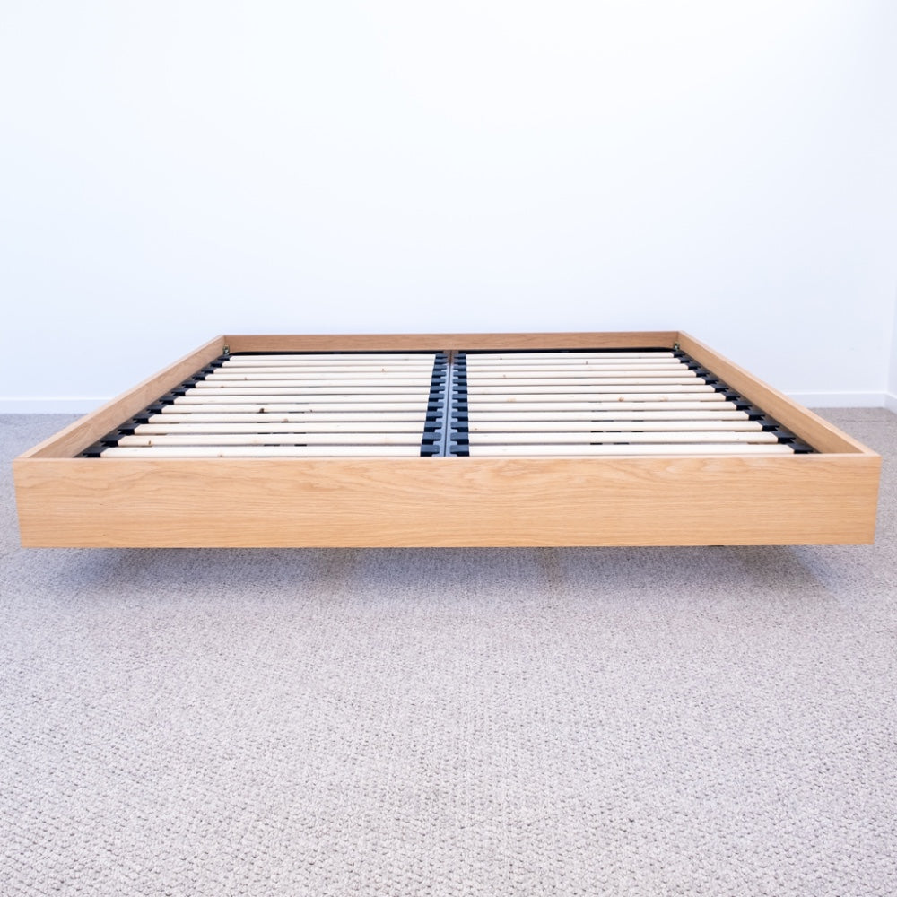 Floating bed base in American Oak, with a green velvet bed head in a master bedroom