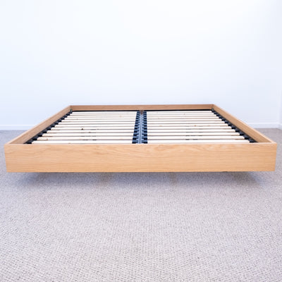 Floating bed base in American Oak, with a green velvet bed head in a master bedroom