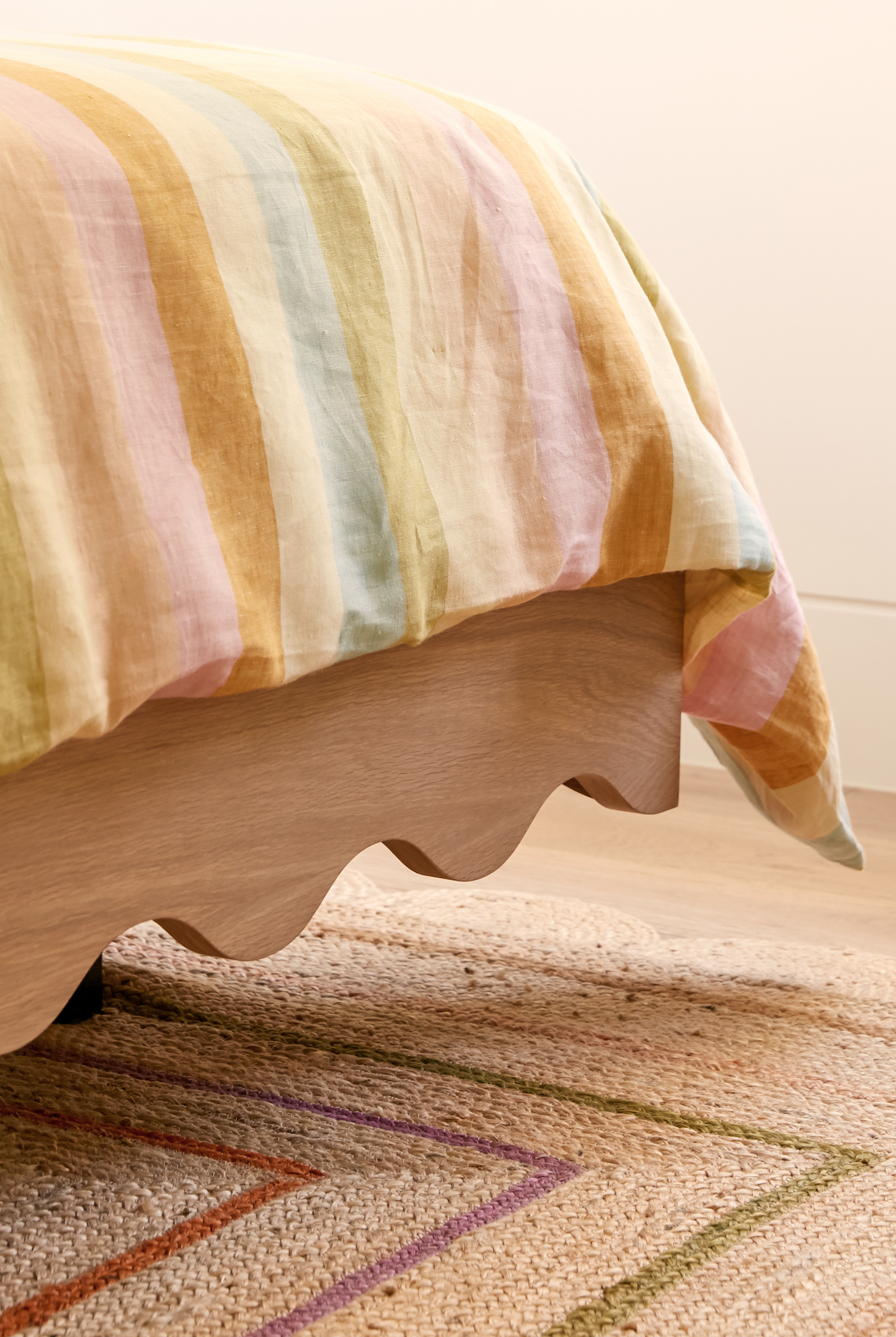 Floating girls bed in timber with curved rails and dressed in striped linen sheets