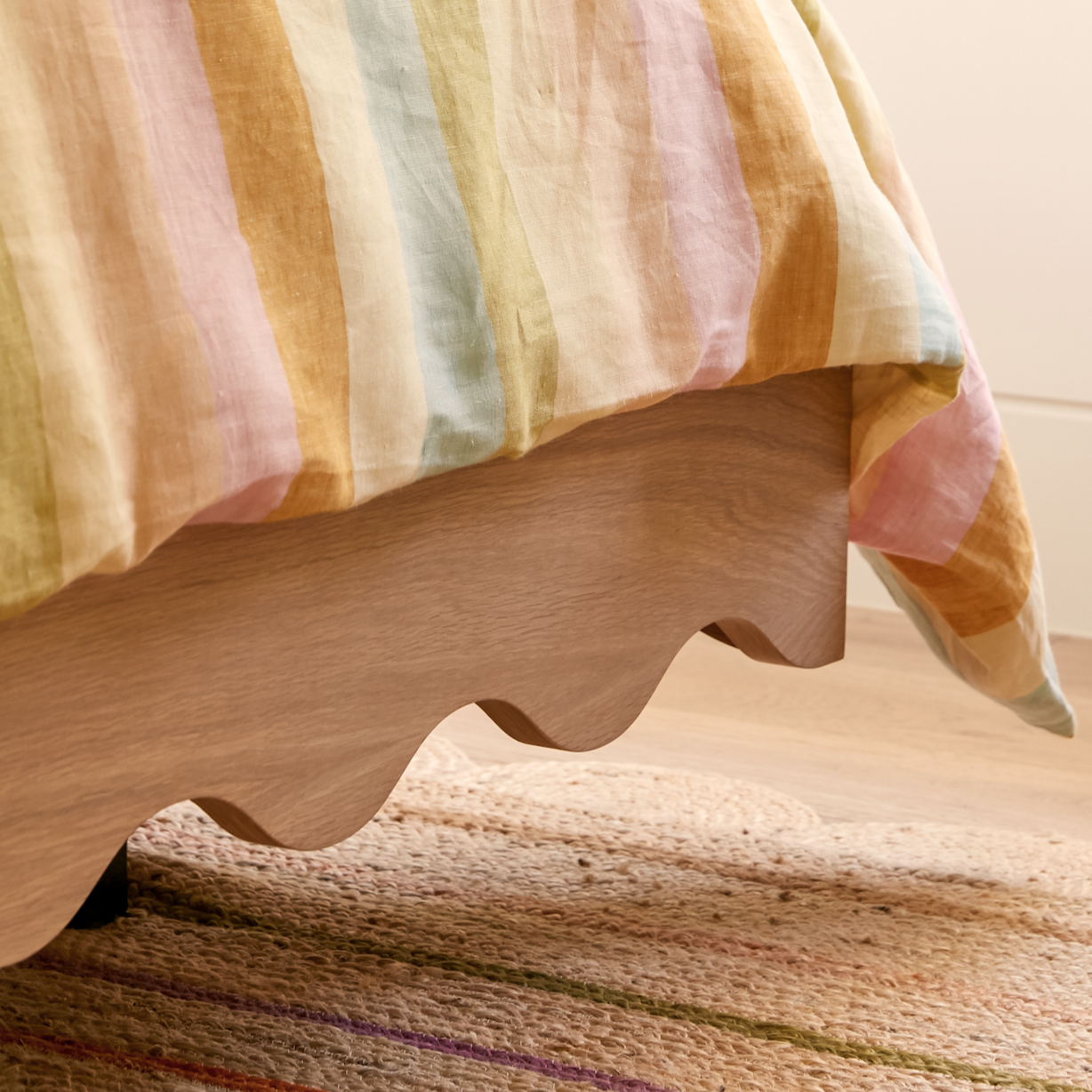 Floating girls bed in timber with curved rails and dressed in striped linen sheets