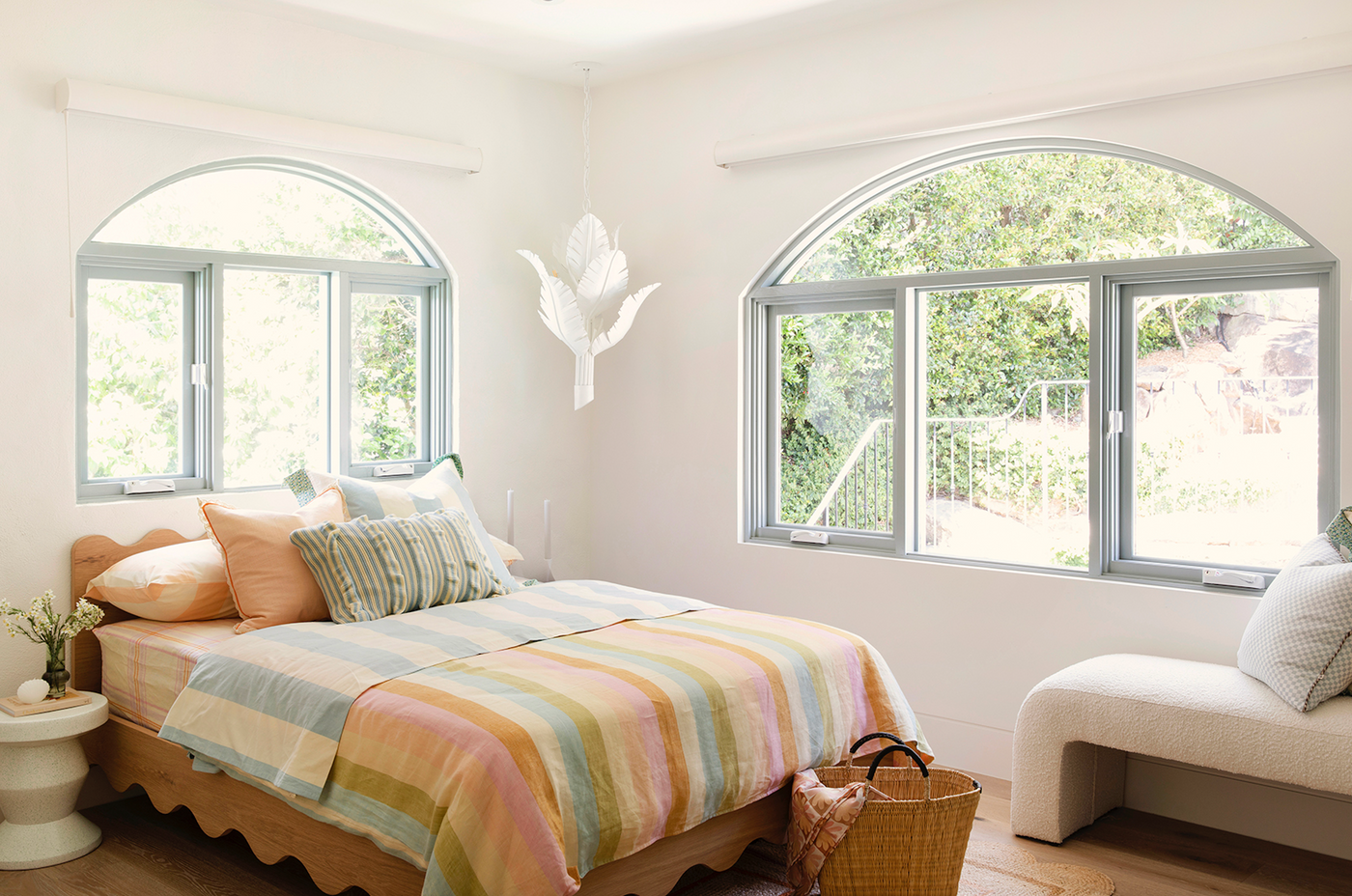 Floating girls bed in timber with curved rails and dressed in striped linen sheets