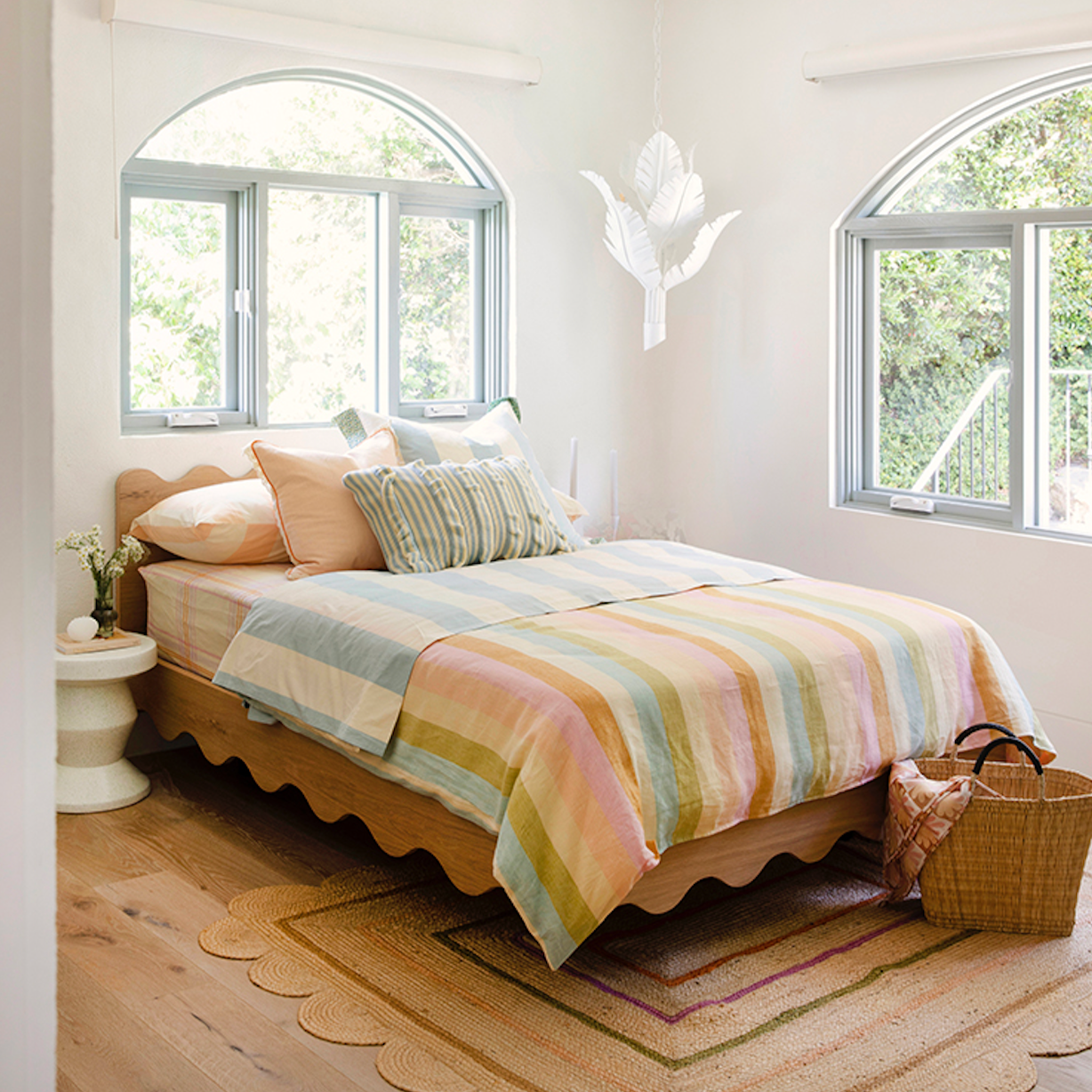 Floating girls bed in timber with curved rails and dressed in striped linen sheets