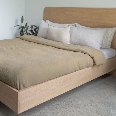 Floating Bed Frame in American Oak, pictured with olive green linen in a guest bedroom. Made in QLD by Create Estate