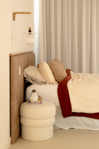 Profile shot of leather look panelled bed head in master bedroom with timber feature strip and sheers drapes to the side