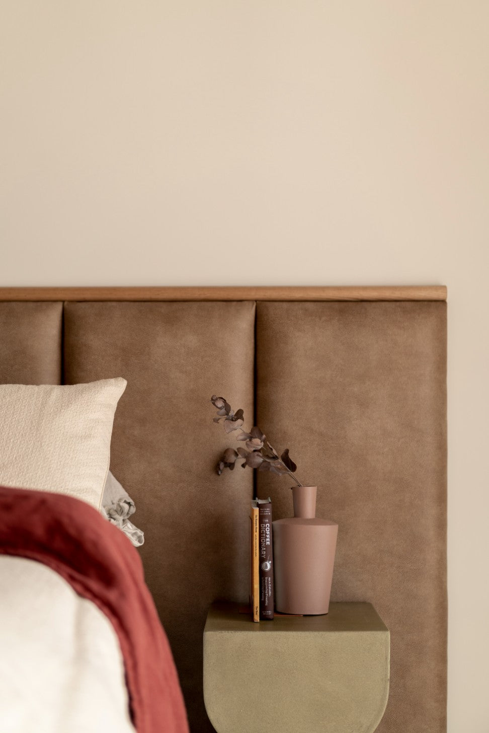 Leather look panelled bed head in master bedroom with timber feature strip and green side table