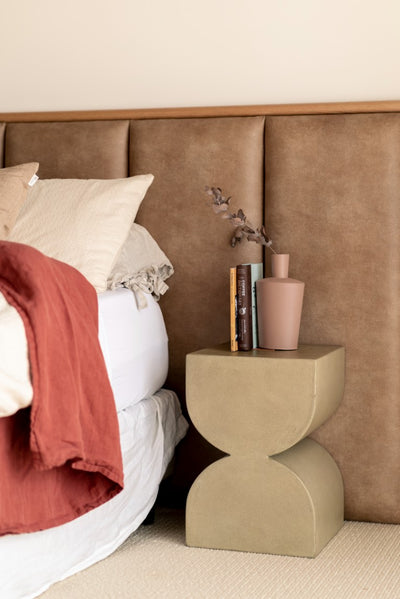 Leather look panelled bed head in master bedroom with timber feature strip and green side table