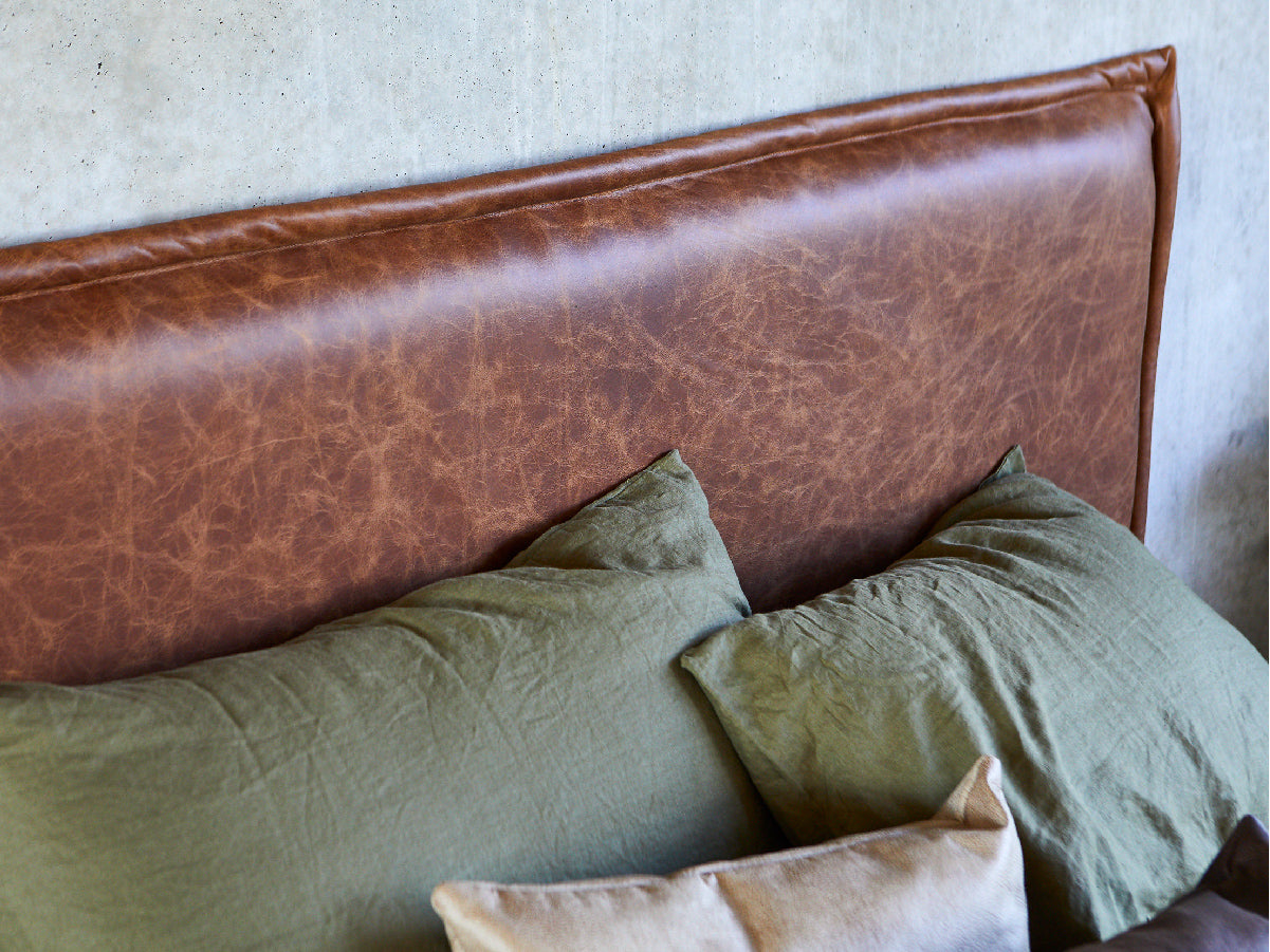 leather bed head made in Australia by Create Estate, pictured with green linen sheets on a concrete wall