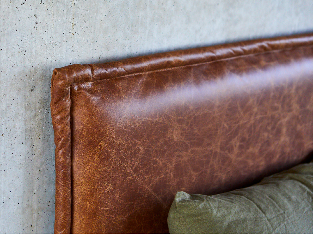 leather bed head made in Australia by Create Estate, pictured with green linen sheets on a concrete wall