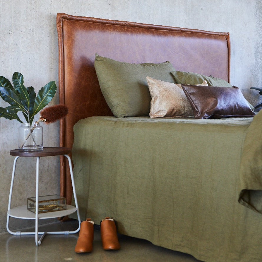 leather bed head made in Australia by Create Estate, pictured with green linen sheets on a concrete wall