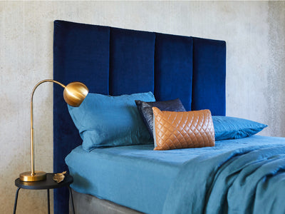 Blue velvet bed head pictured with blue linen sheets against a concrete bedroom. Made in Australia by Create Estate